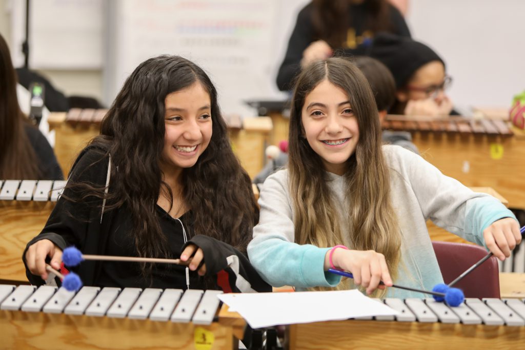 Two students posing while playing instruments